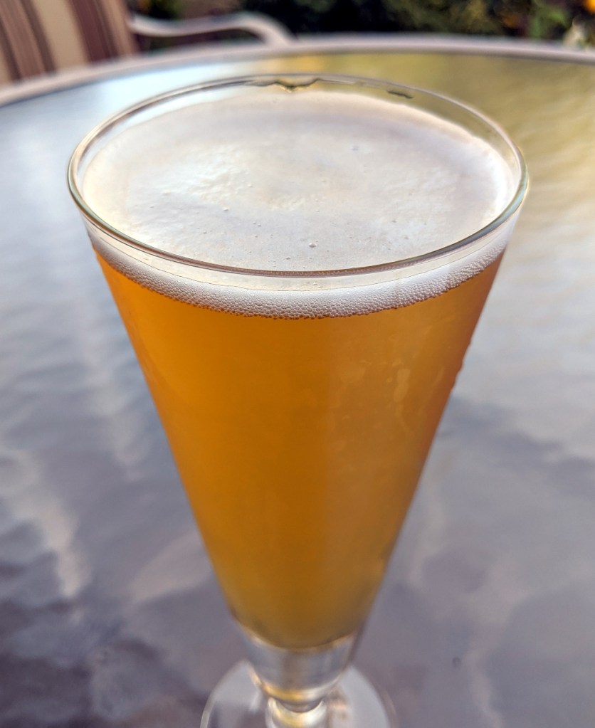 golden beer with white head in conical pilsner glass