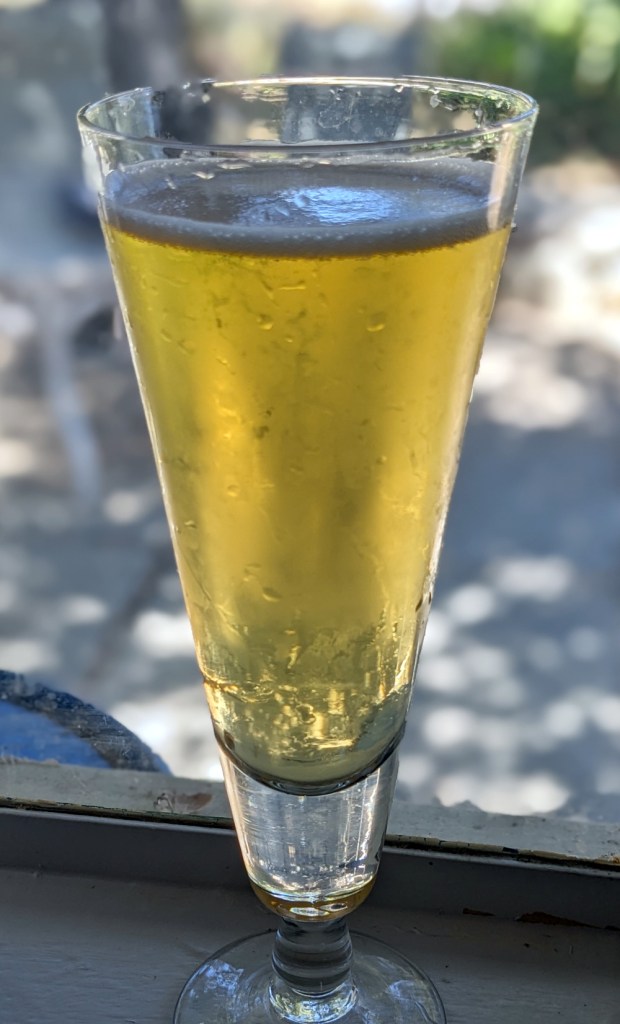 pale yellow beer with white head in conical pilsner glass